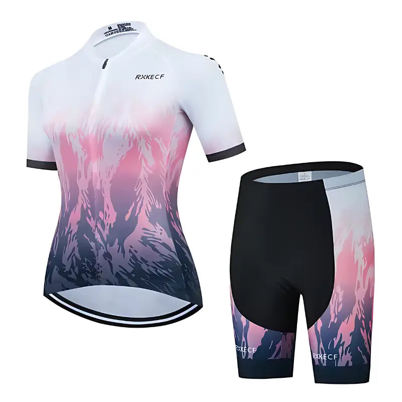 Roupa de ciclismo feminina com camisa e shorts com um desenho de paisagem de montanha em gradientes rosa, roxo e branco.