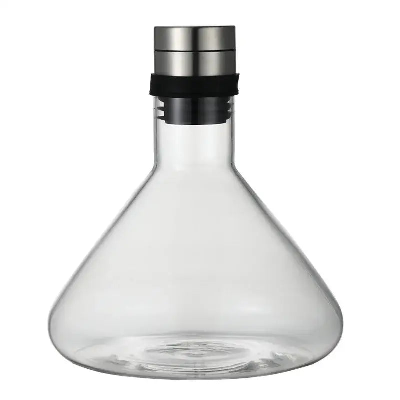 Decanter de vidro com base larga e rolha metálica.