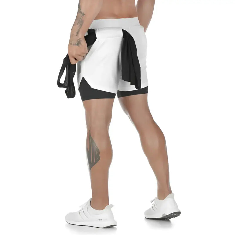 Shorts esportivos com uma camada externa branca e uma camada interna preta, usados por uma pessoa com uma tatuagem visível na perna.