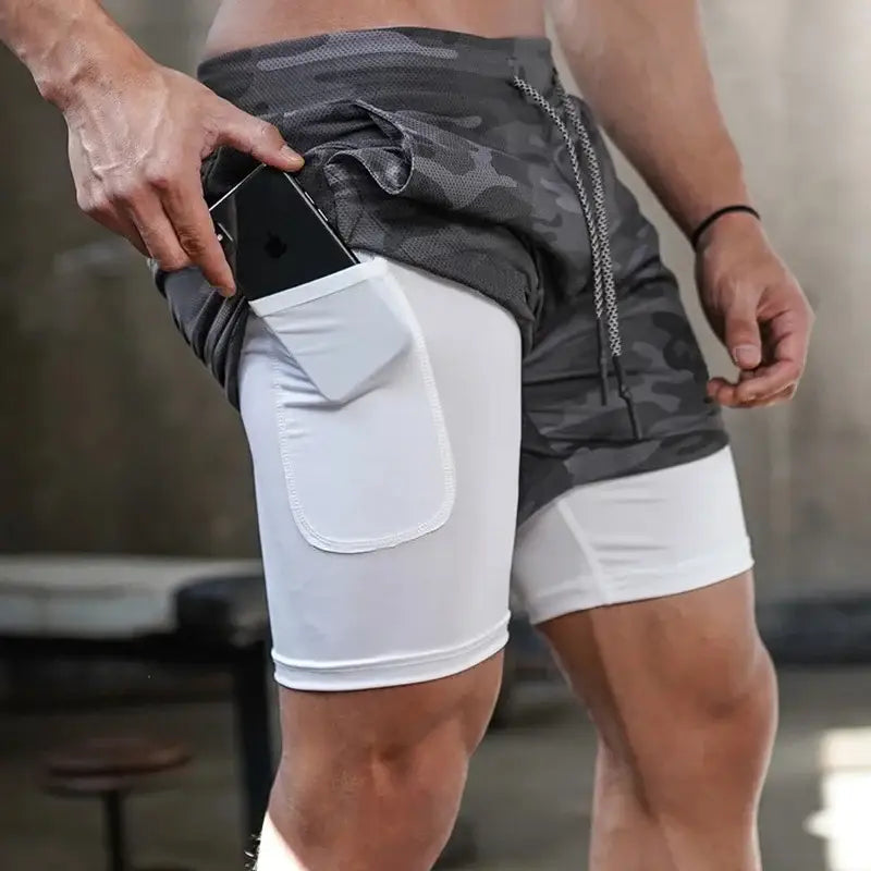 Shorts esportivos de duas camadas com camada de compressão branca por baixo e camada externa de camuflagem cinza.